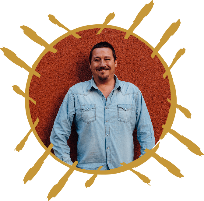 Portrait of Jonathan Horan in a blue shirt with gold sunburst frame